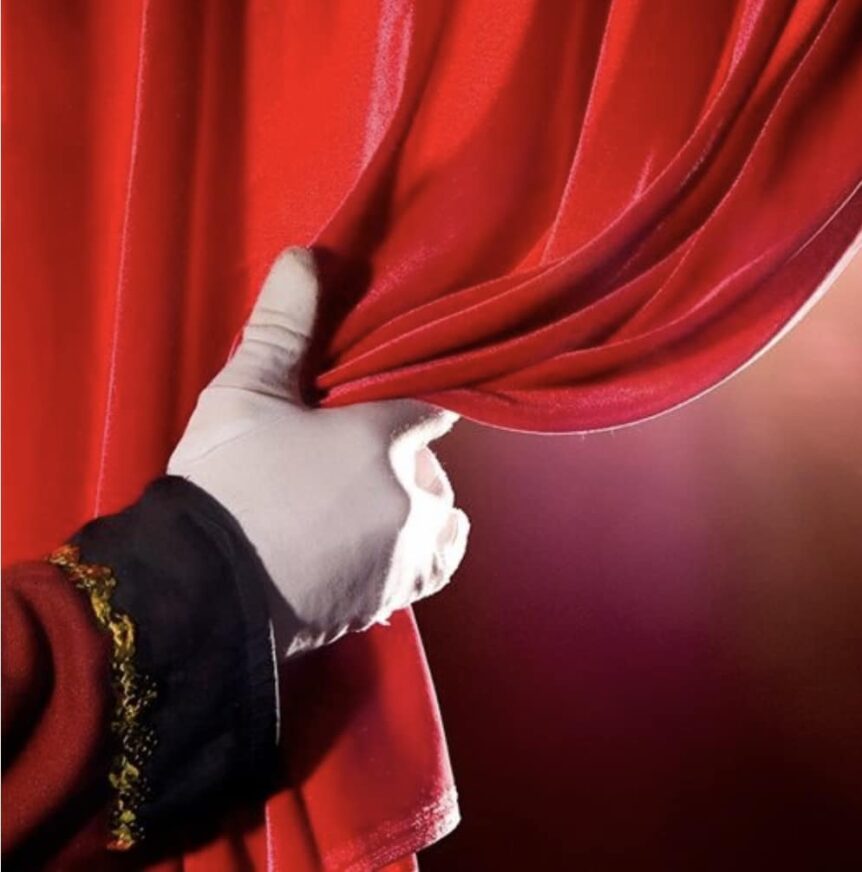 A gloved hand pulling aside a red curtain
