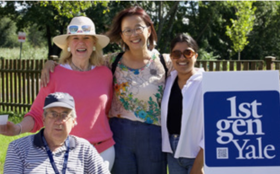 Four people outside smiling and holding a large 1stGenYale sign
