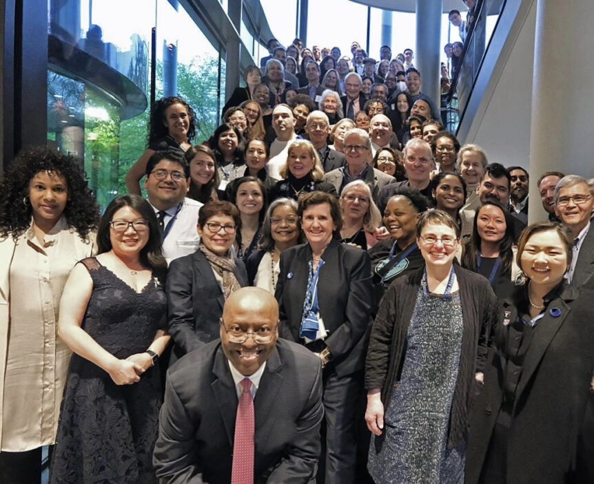 Dozens of alumni stand on a staircase at the Yale School of Management