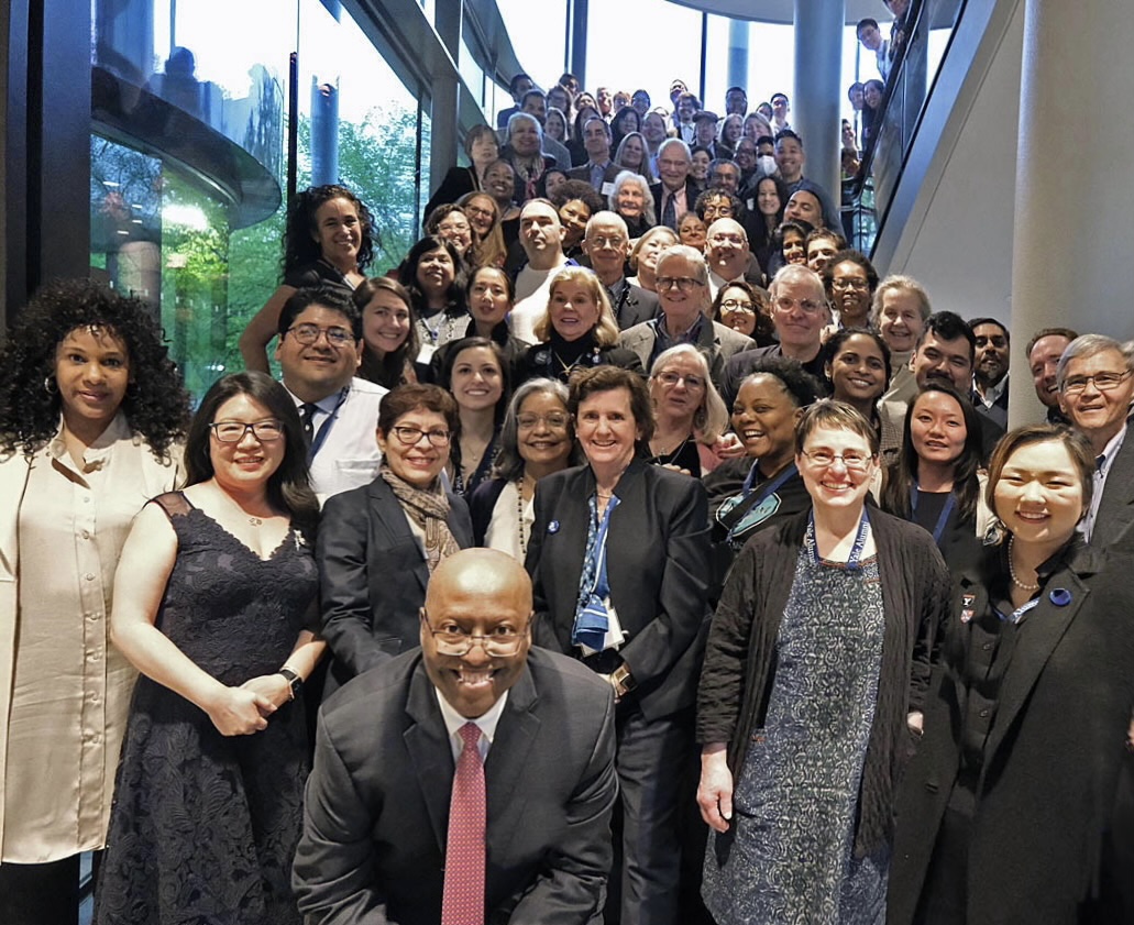 Dozens of alumni stand on a staircase at the Yale School of Management