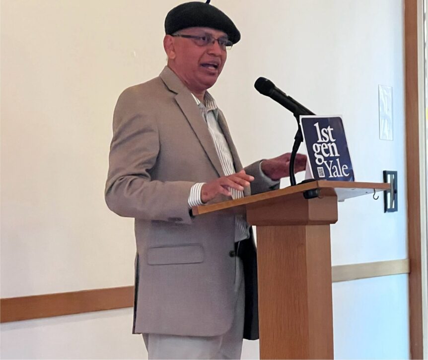 An alum stands and speaks at a podium with a 1stGenYale sign